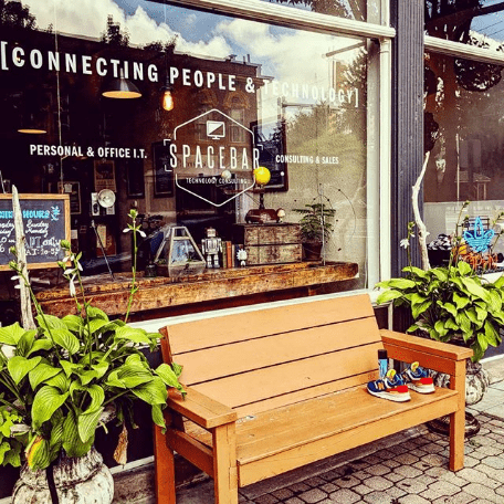 A wooden bench and potted plants outside the original Main Street storefront.