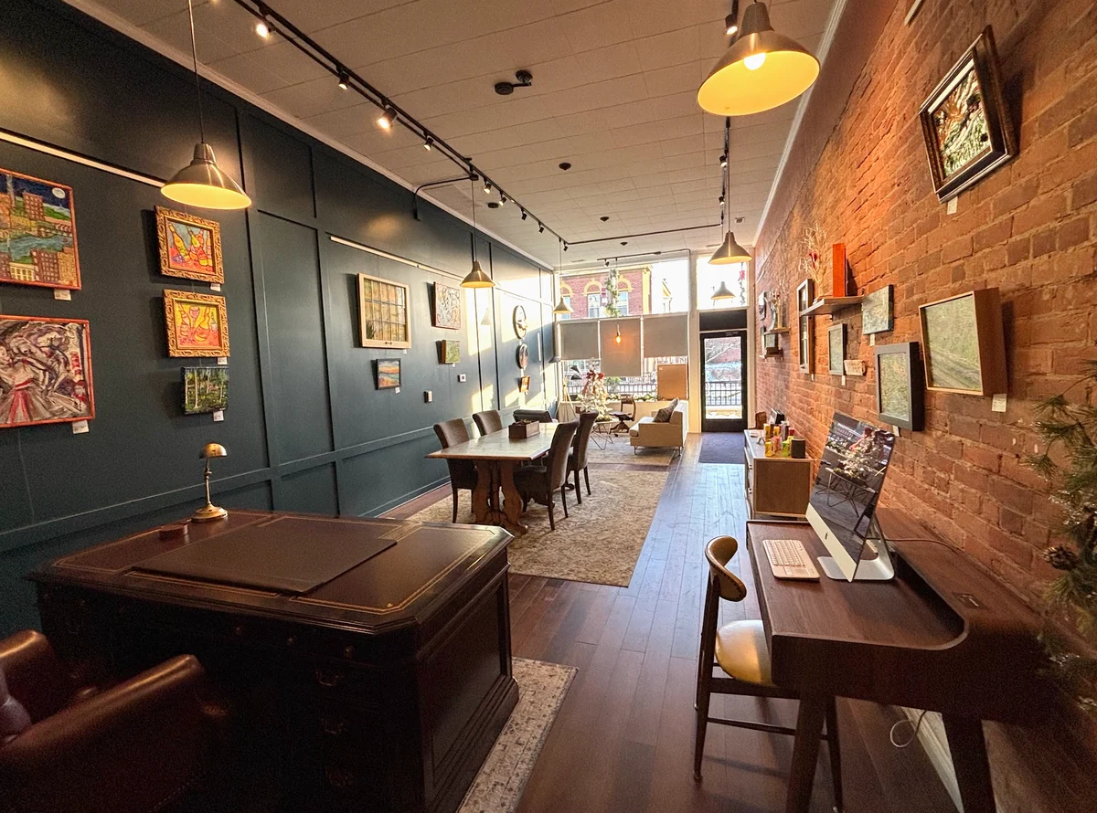 Interior of Spacesicle with desks, a meeting table, artwork, and exposed brick.